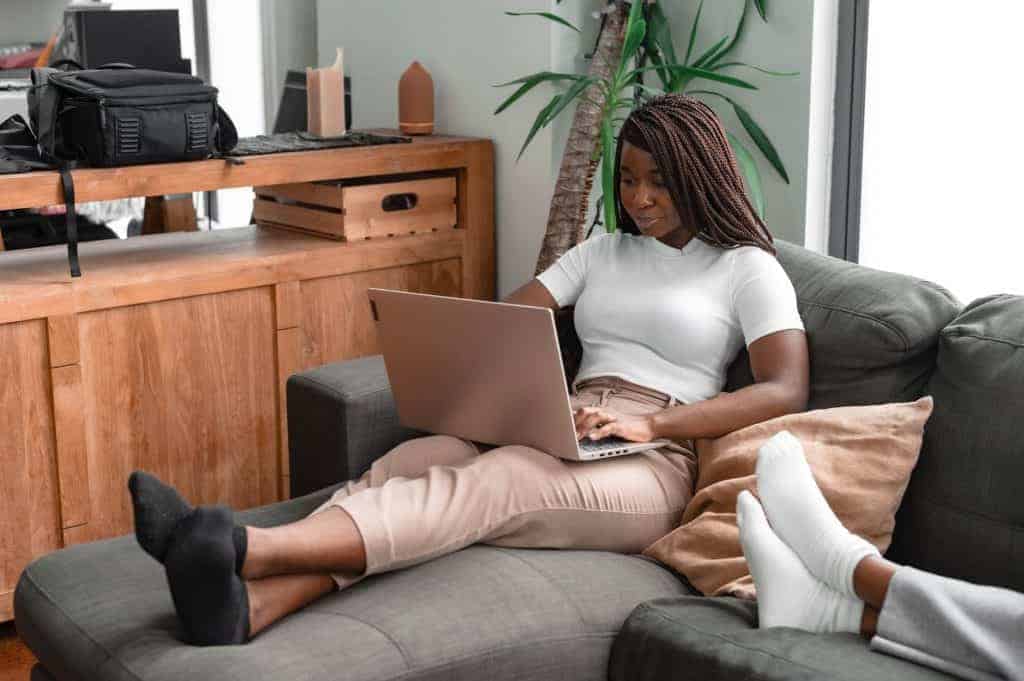 a woman using a laptop while sitting on a couch