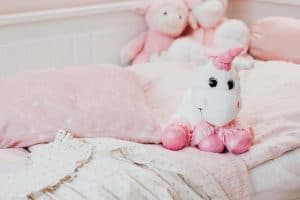 white and pink unicorn plush toy on bed