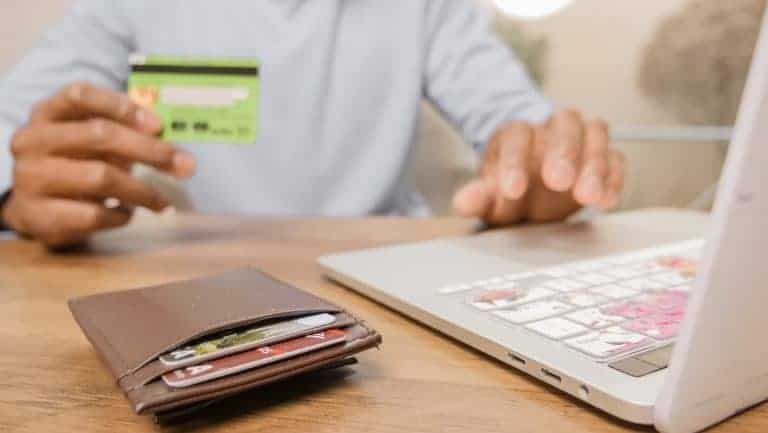 a person holding a bank card while using a laptop